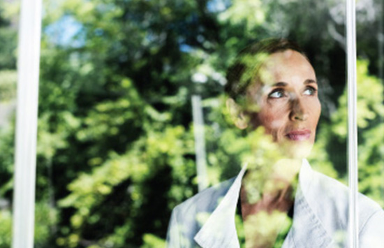 Woman looking out of office window at green trees