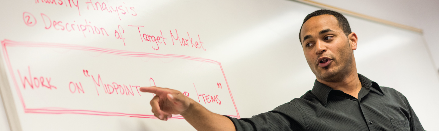 Adjunct faculty member speaking at white board during class