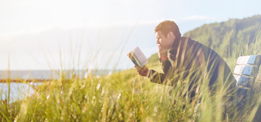 Student reading scripture by the ocean