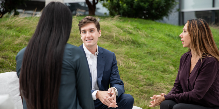 Three students sitting outside West LA campus talking together